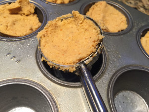Using a cookie scoop, add masa to the mini muffin tin.